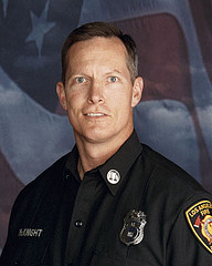 Head shot of Captain McKnight, a white male in uniform with the American Flag behind him.