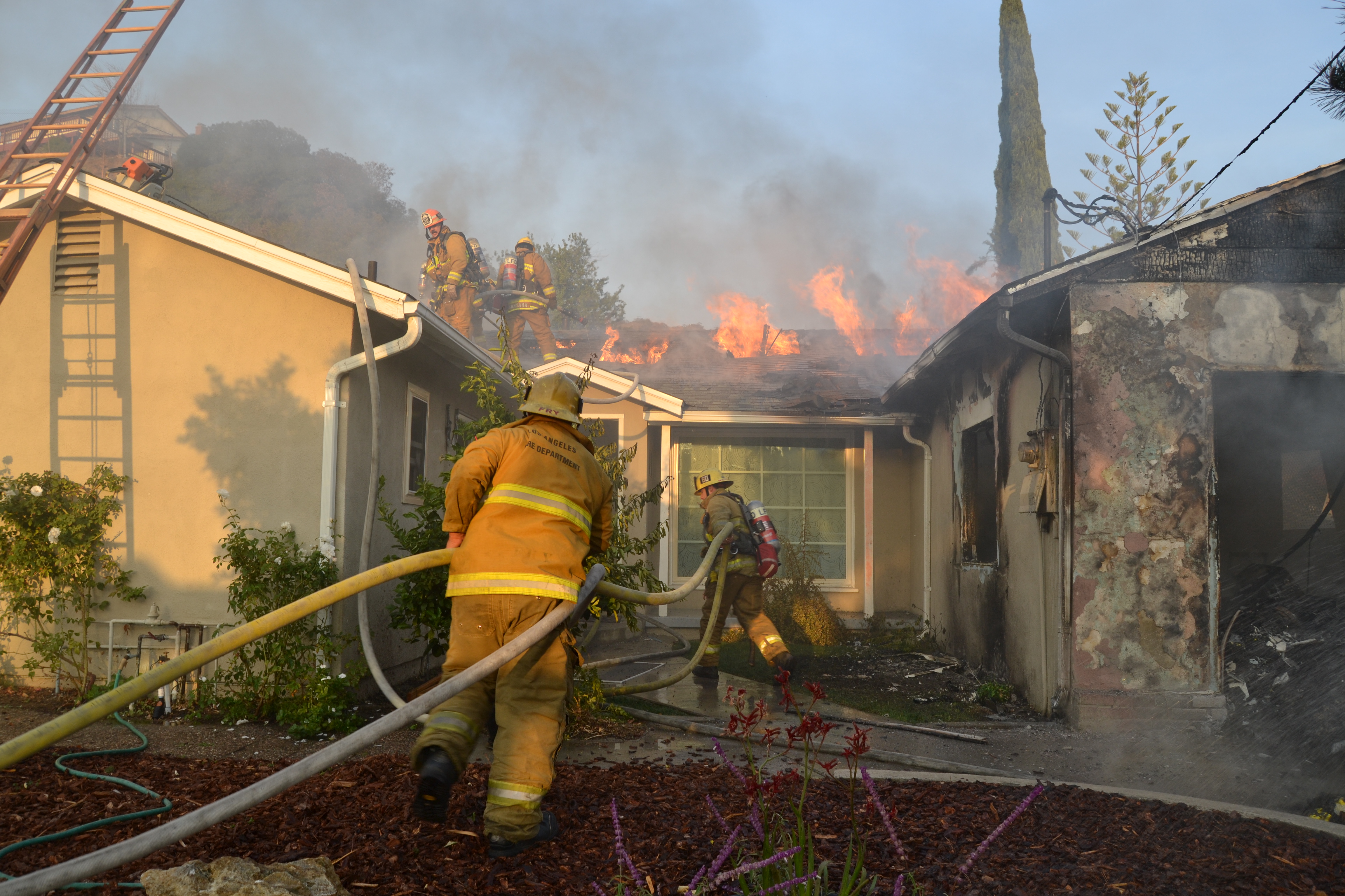 Firefighters Advance Hoselines on Burning Home in Sun Valley