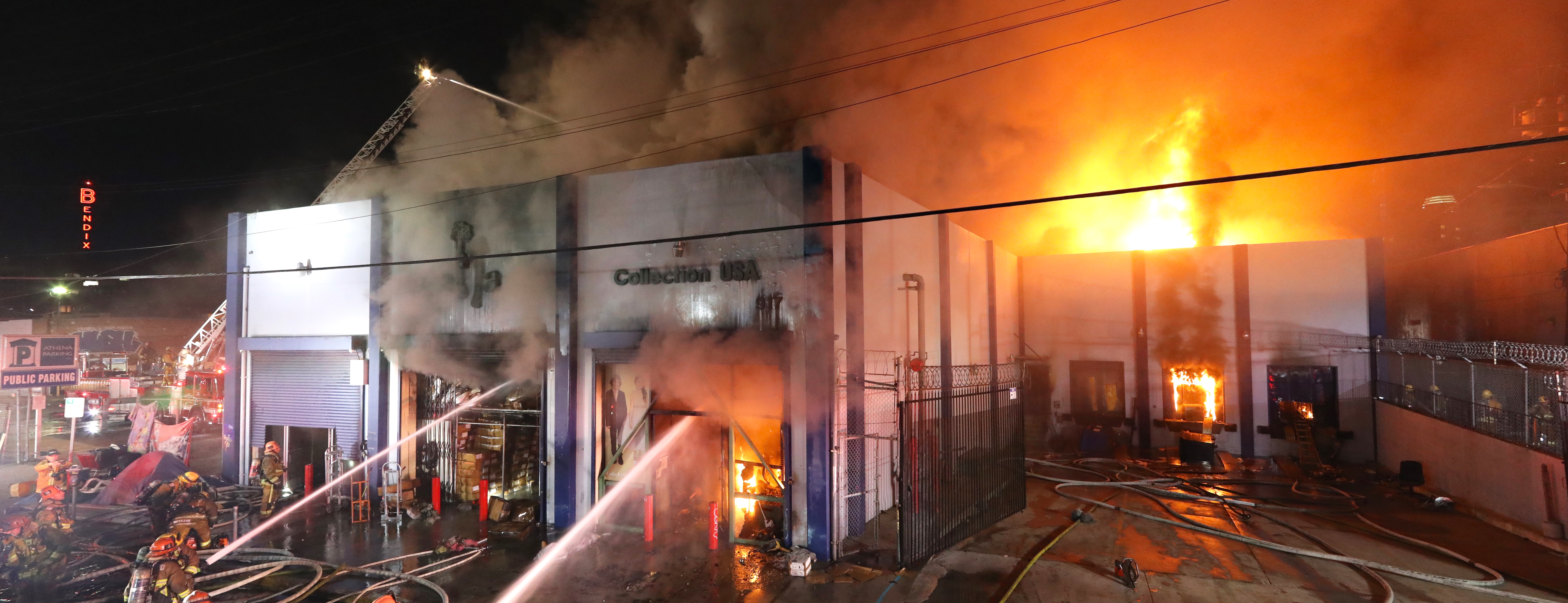 Large commercial building with fire showing an numerous fire engines with firefighters fighting the fire
