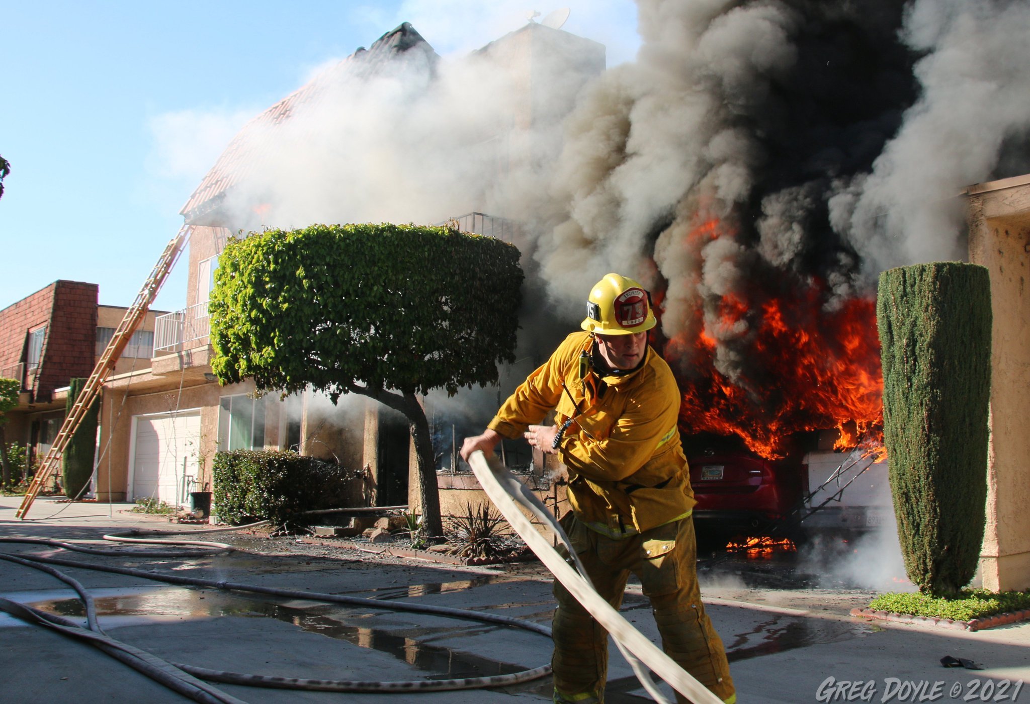 Firefighter pulling handline in front of burning building
