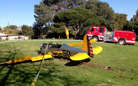 Small single engine yellow plane on golf course grass.
