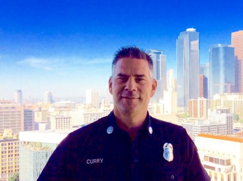 Headshot of Captain Curry in uniform with the Los Angeles skyline in background.