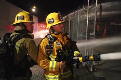 Two firefighters spraying water.