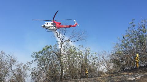 Helicopter making water drop over brush fire