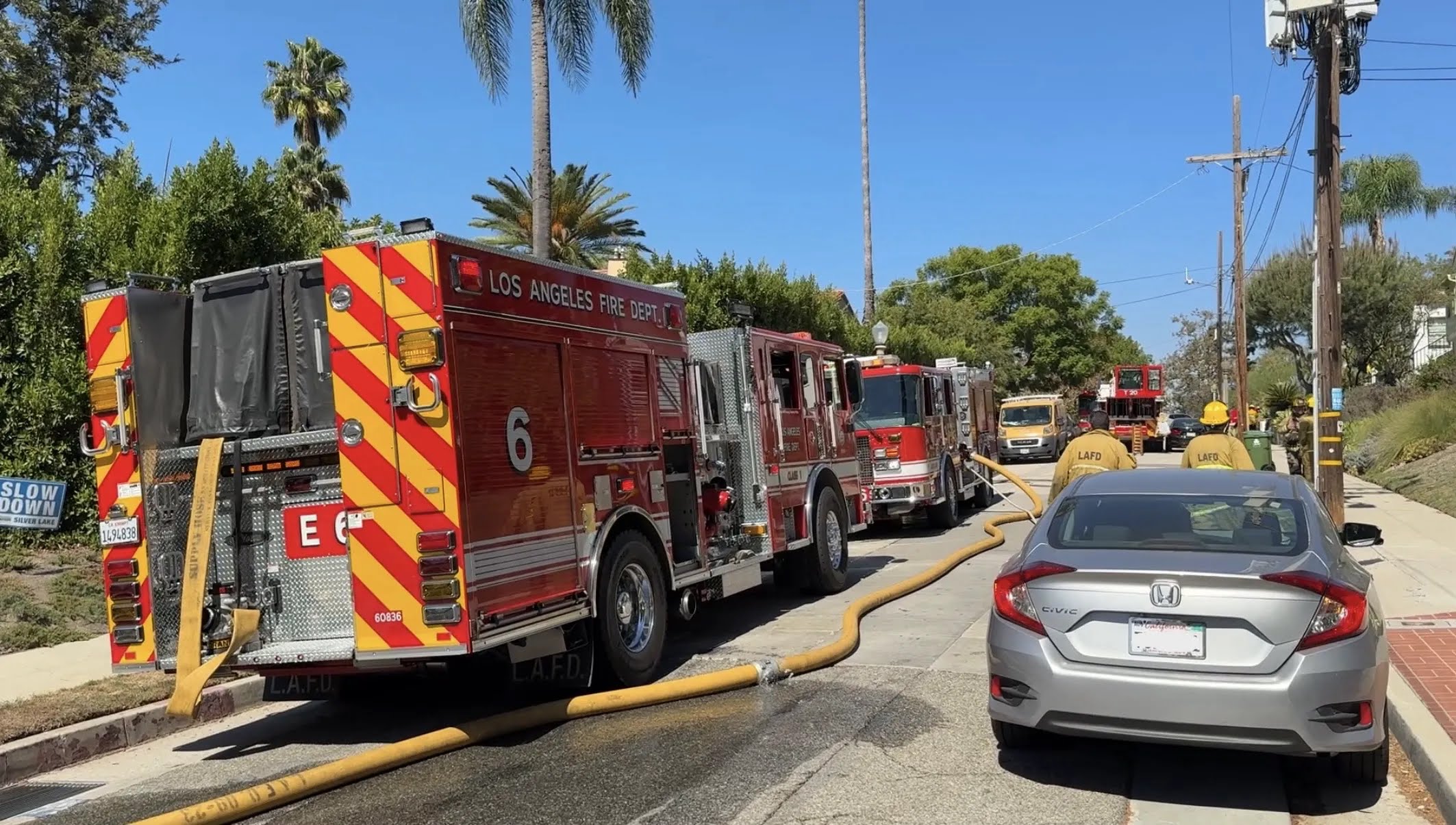 LAFD Engine 6 and apparatus parked on residential street with supply hose connected during incident response.