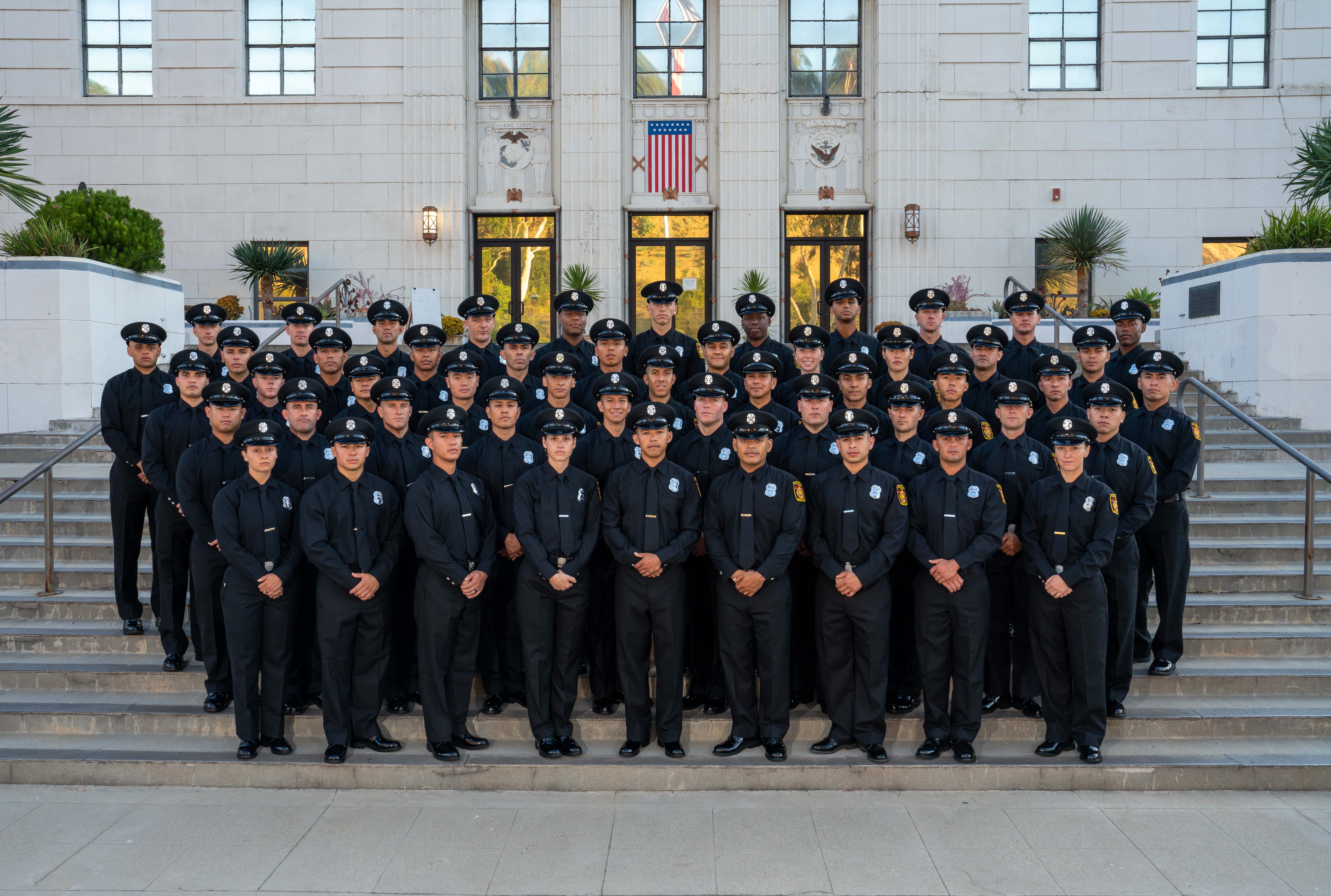 All 52 graduates in dress uniform for group photo on stairs in front of training center