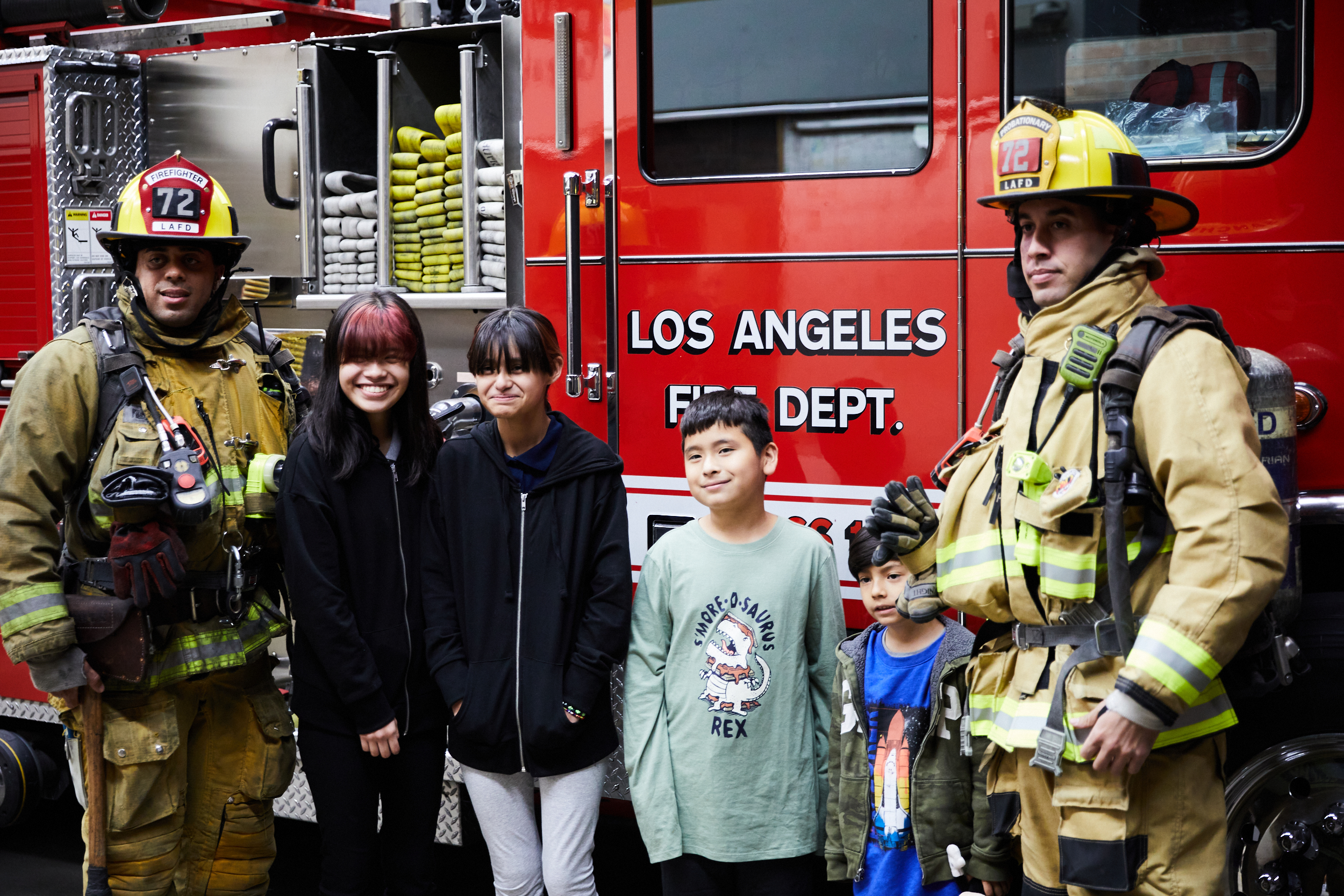 Two firefighters and the children in front of the fire engine