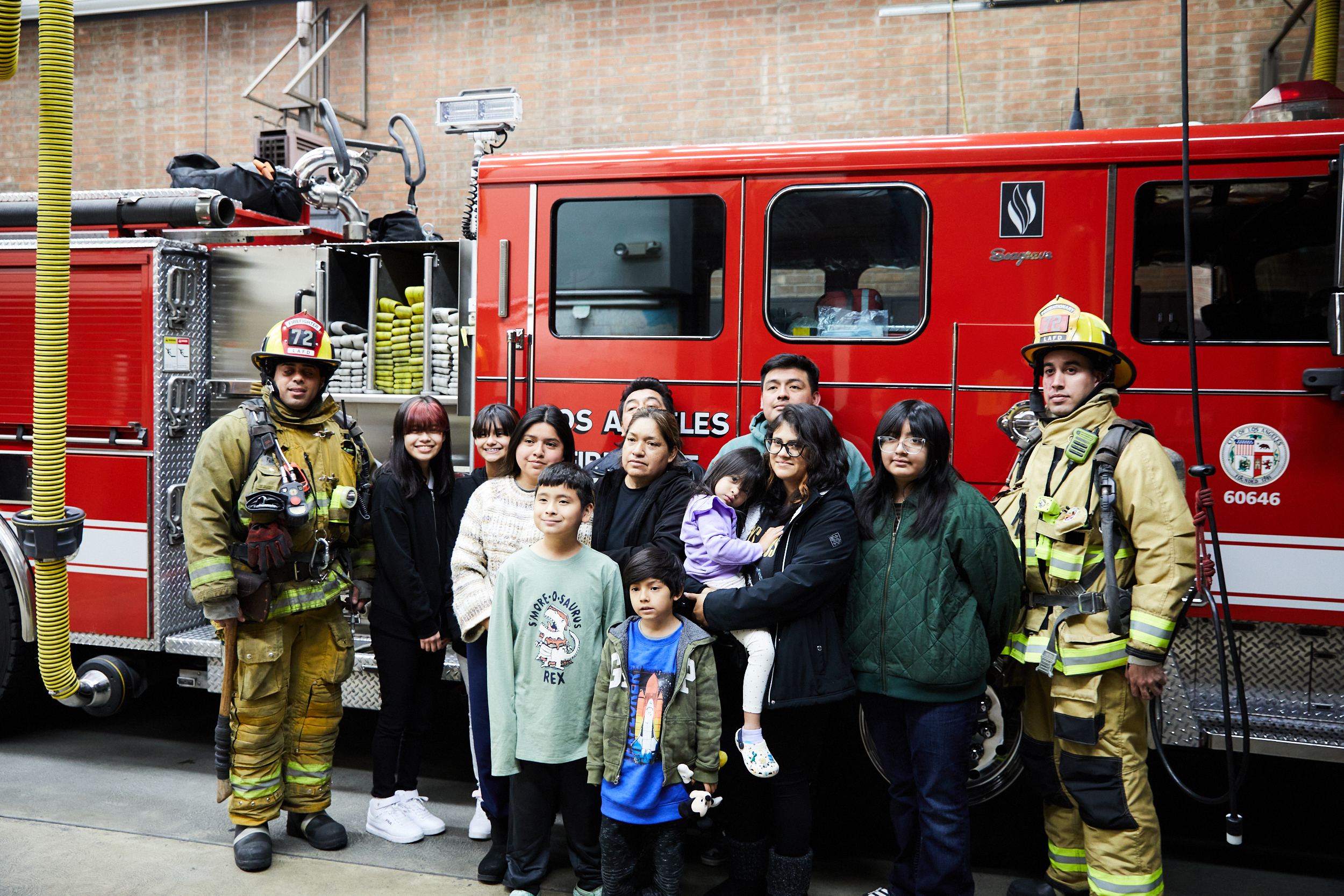 The two Mendoza families pictured with firefighters in front of fire engine