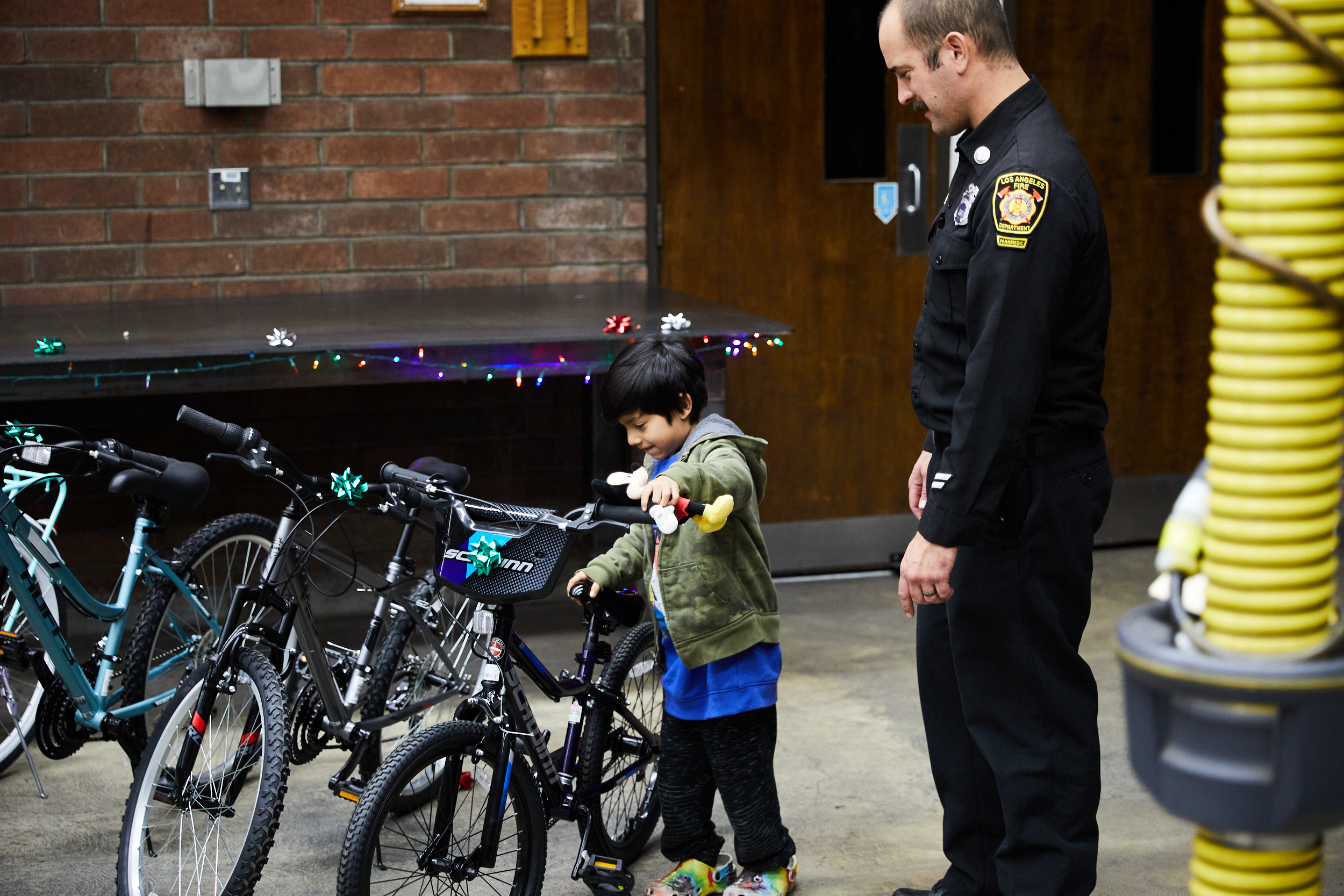Fire captain pictured with young boy smiling while looking at new bike
