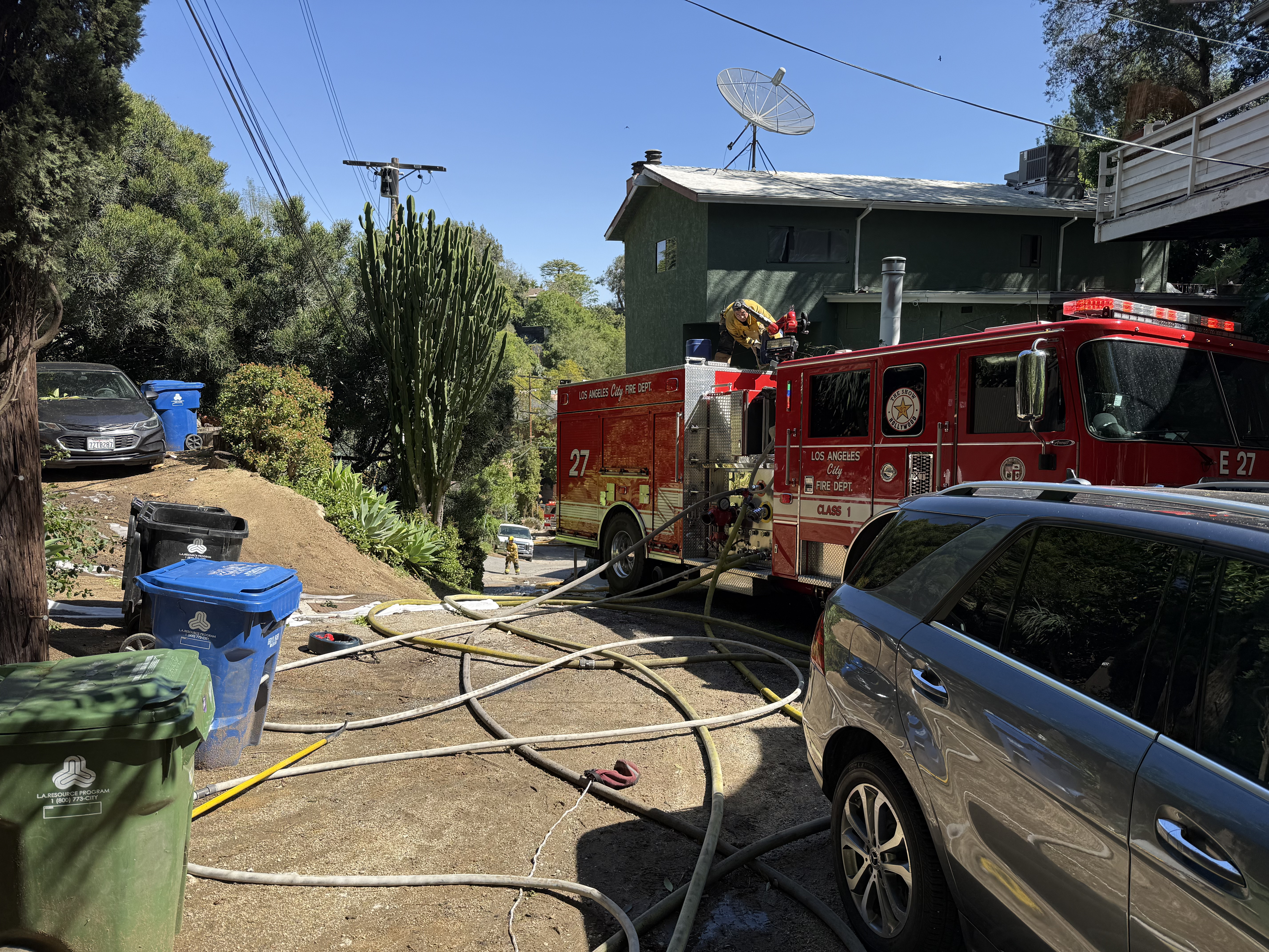 Fire engine 27 seen with hose lines coming off the engine, staged in front of the fire unit.