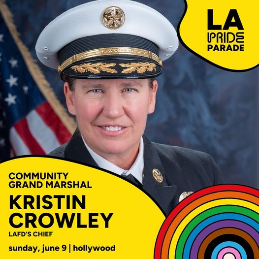 Los Angeles City Fire Department Chief Kristin Crowley smiles in her official uniform and  hat with an American Flag in the background.   "L.A. Pride Parade, Community Grand Marshal Kristin Crowley. LAFD's Chief. Sunday, June 9. Hollywood.